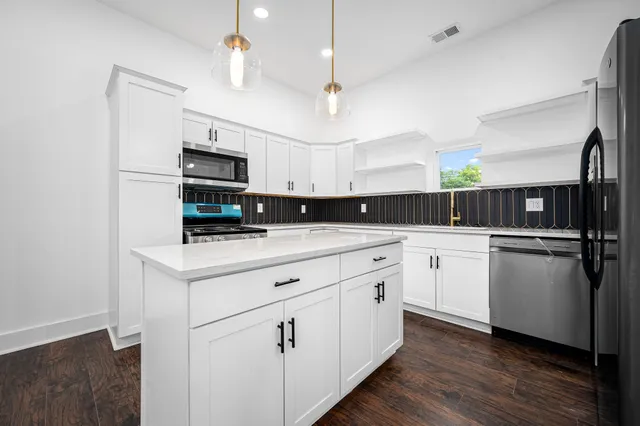 a kitchen with kitchen island white cabinets and refrigerator