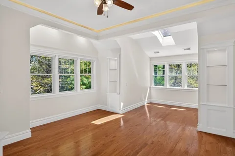 an empty room with wooden floor fan and windows