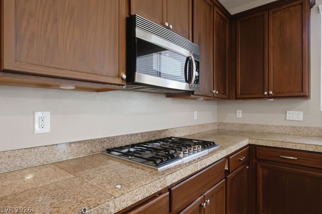 9712 North Running Rabbit Street Las Vegas, NV 89143 - Photo 18 of 42 A well-appointed kitchen features rich wood cabinetry, durable granite countertops, and modern stainless steel appliances.