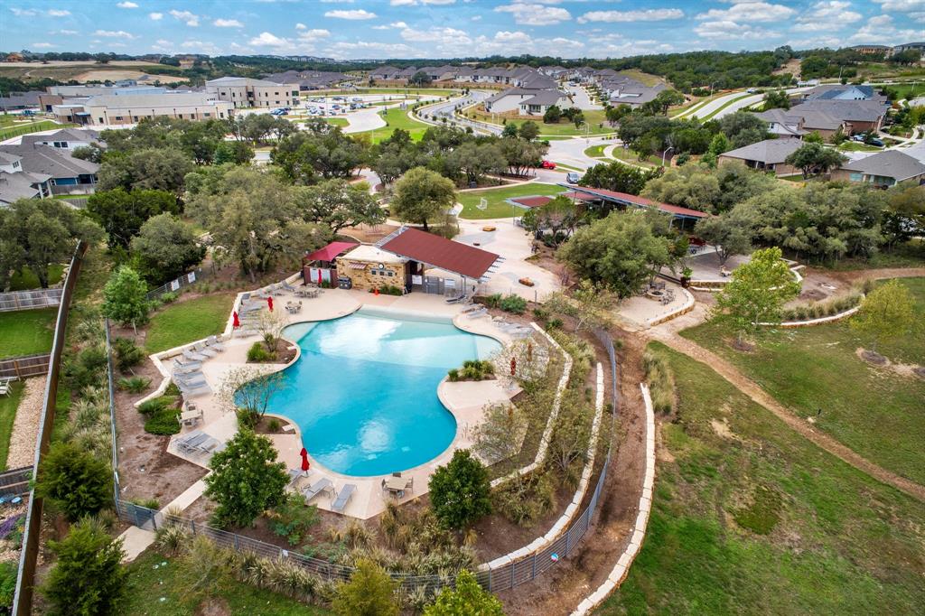 1012 Quarry Point Pass Leander, TX 78641 - Photo 32 of 39 An aerial view showcases the community pool with ample lounge seating, framed by mature trees and residential landscapes.