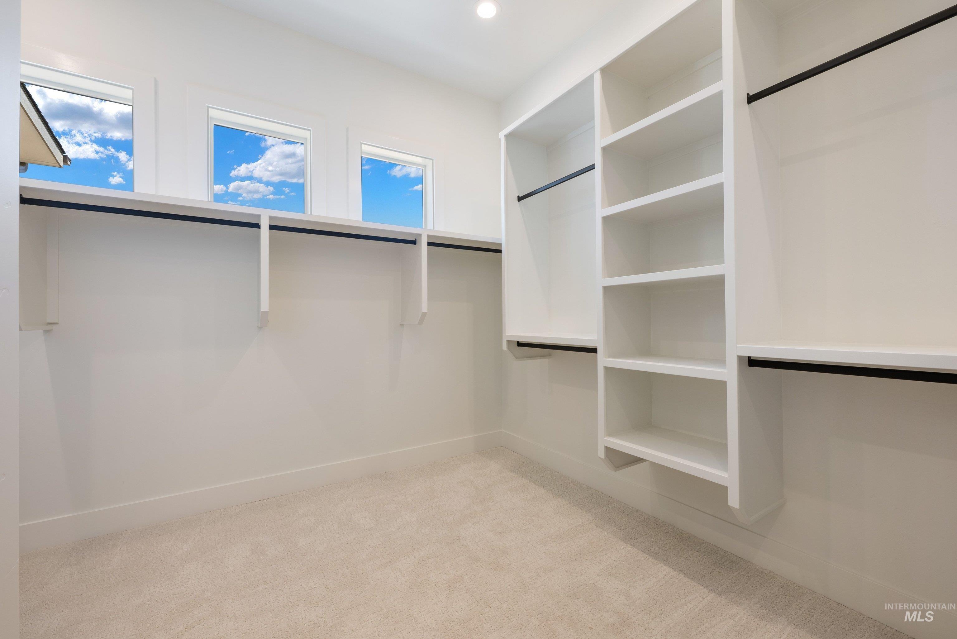 24763 Ardmore Court Caldwell, ID 83607 - Photo 35 of 50 Spacious walk-in closet featuring light beige carpeting, multiple built-in shelving units, and ample hanging rod space