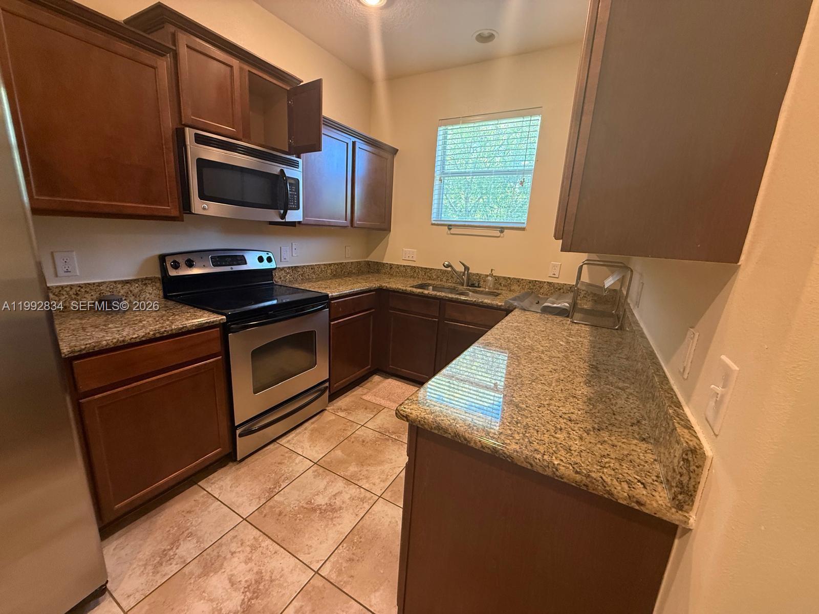 3154 Rodrick Circle Orlando, FL 32824 - Photo 8 of 21 a kitchen with granite countertop a sink a stove top oven and cabinetry