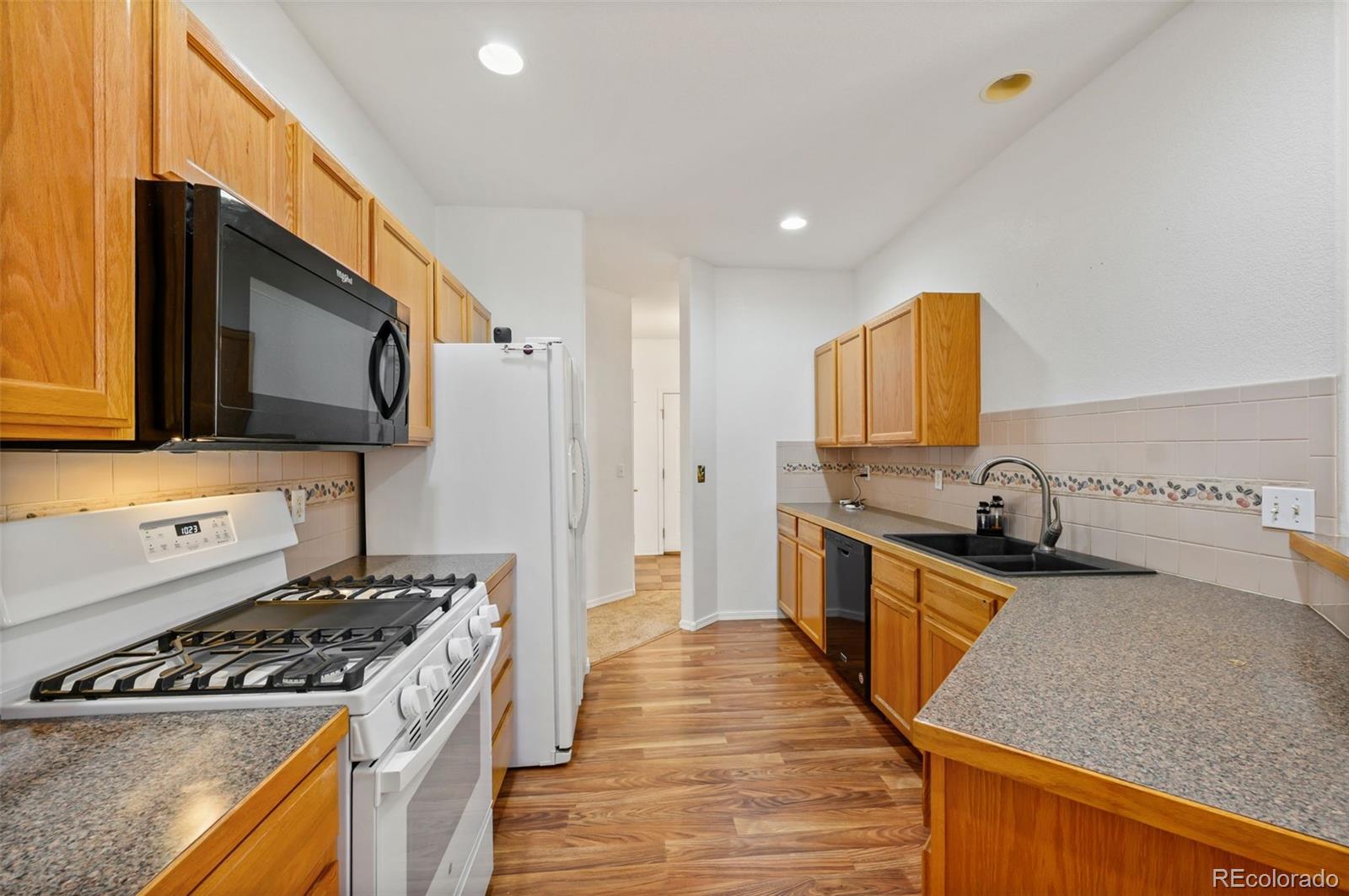 203 Hubbell Street Berthoud, CO 80513 - Photo 18 of 49 a kitchen with stainless steel appliances granite countertop a stove a sink and a microwave