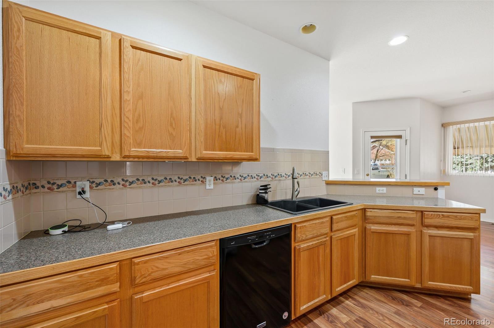 203 Hubbell Street Berthoud, CO 80513 - Photo 19 of 49 a kitchen with stainless steel appliances granite countertop a sink and cabinets with wooden floor