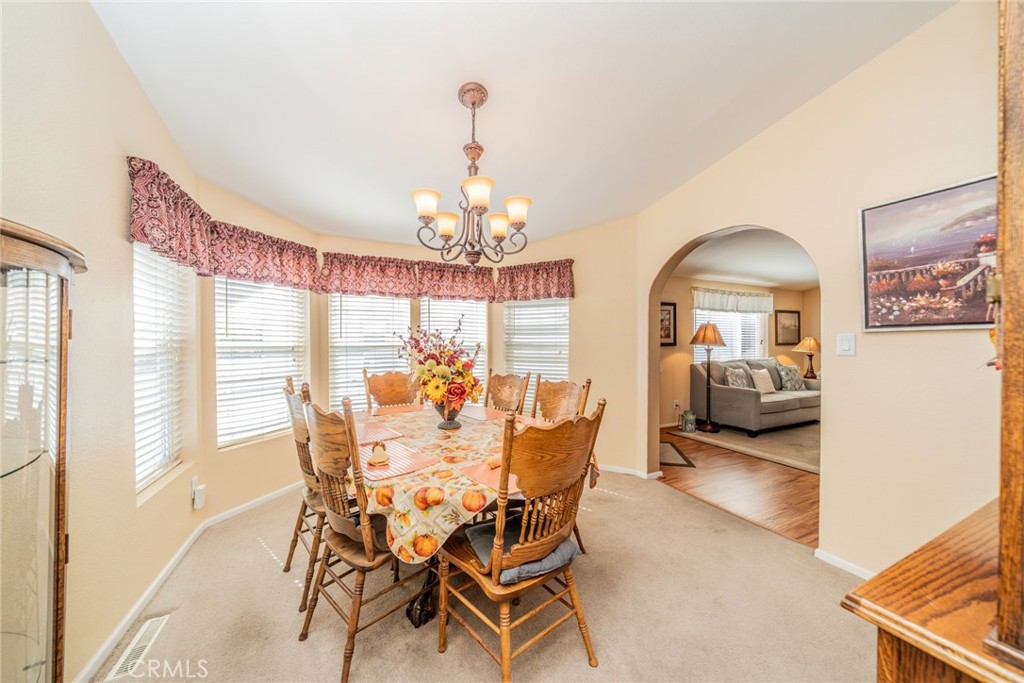 22241 Nisqually Road, Unit 118 Apple Valley, CA 92308 - Photo 17 of 56 a view of a dining room with furniture a chandelier and large windows