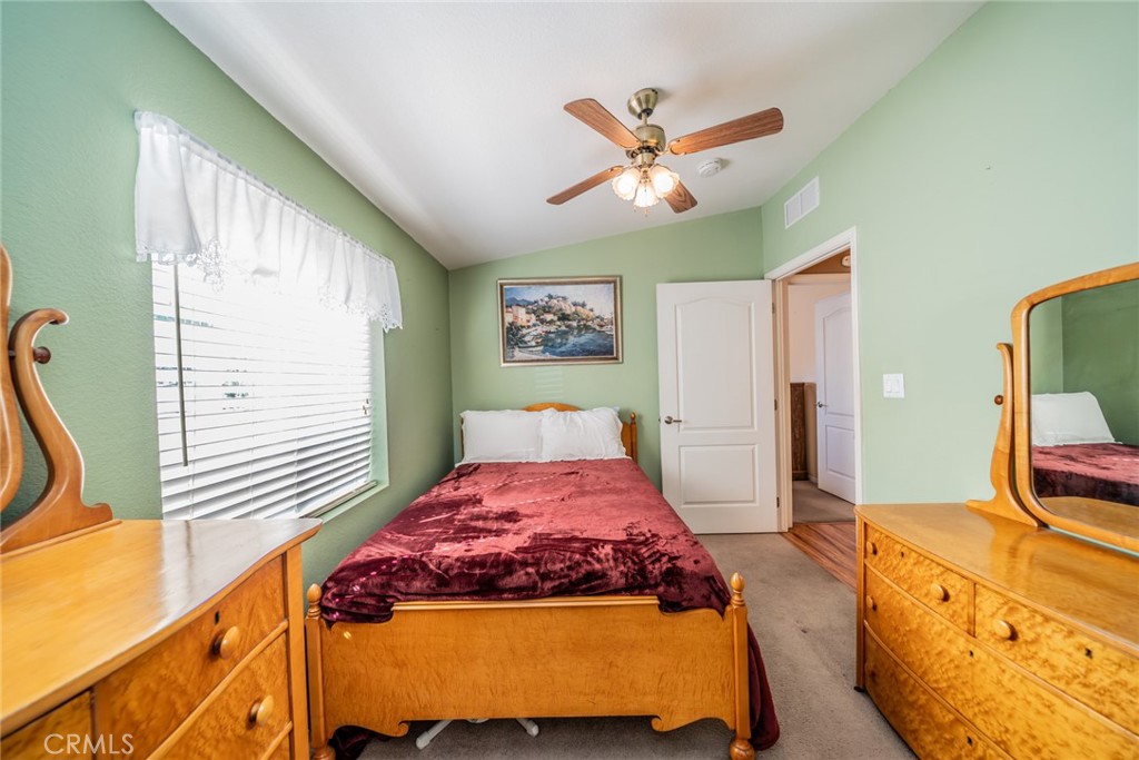 22241 Nisqually Road, Unit 118 Apple Valley, CA 92308 - Photo 21 of 56 a bedroom with a bed a dresser and potted plants next to a window