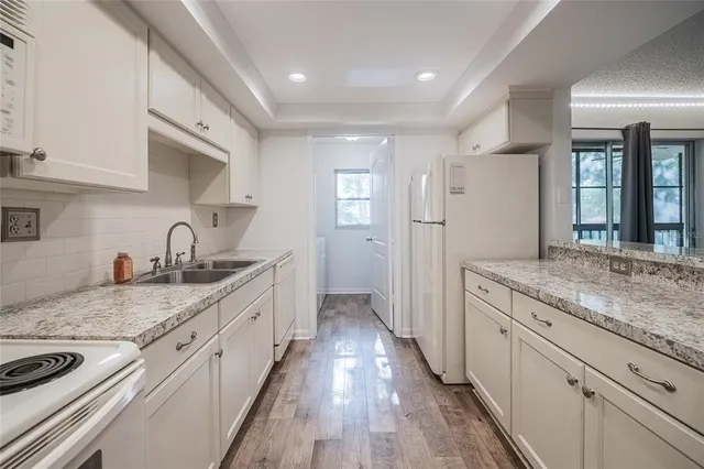 a large kitchen with granite countertop a sink and dishwasher stove a refrigerator with wooden cabinets