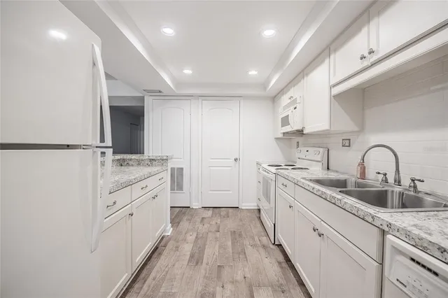 a kitchen with granite countertop white cabinets and white appliances
