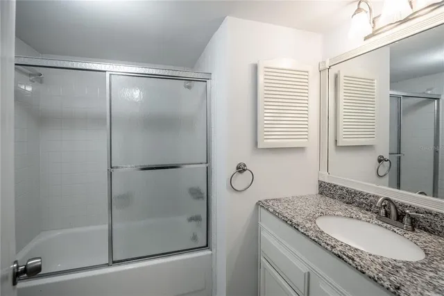 a bathroom with a granite countertop sink a mirror and shower
