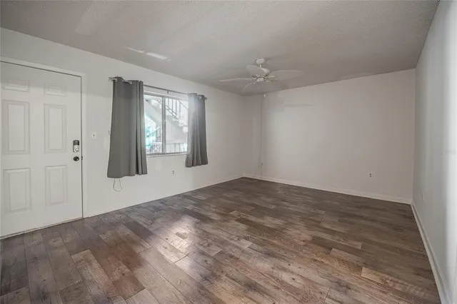 a view of empty room with wooden floor and fan