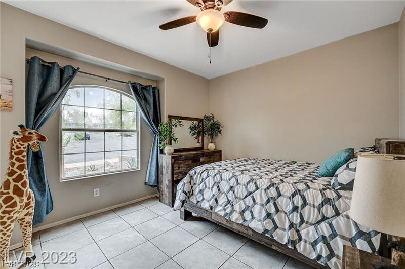 987 Cutter Street Henderson, NV 89011 - Photo 12 of 17 A restful bedroom with arched window views and a gentle ceiling fan for comfort.
