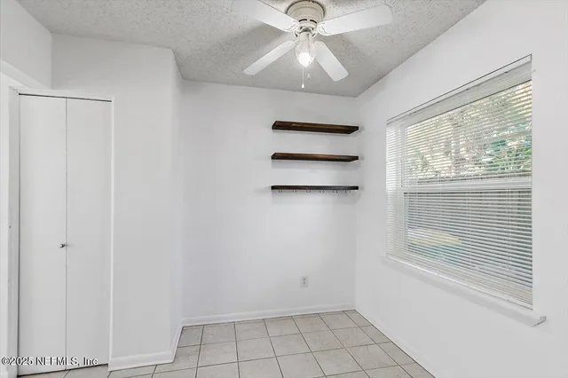 an empty room with windows and fan