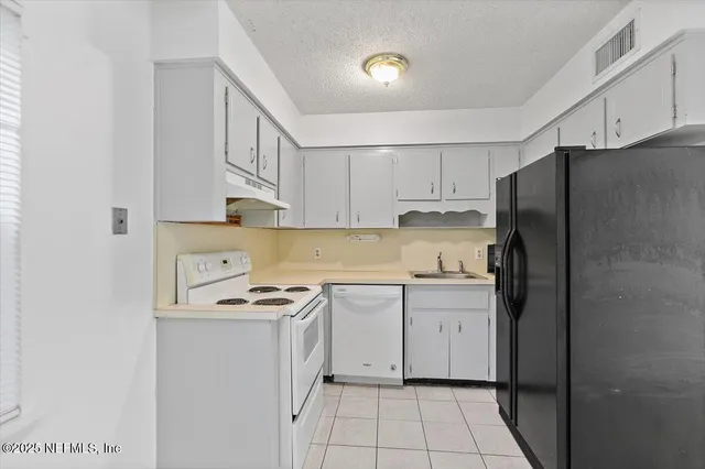 a kitchen with stainless steel appliances granite countertop a refrigerator sink and white cabinets
