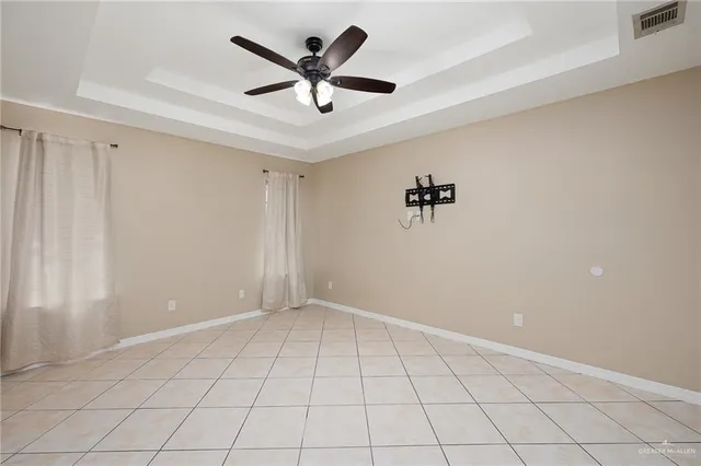 an empty room with ceiling fan and windows