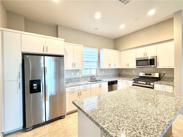 a kitchen with granite countertop a refrigerator and a sink