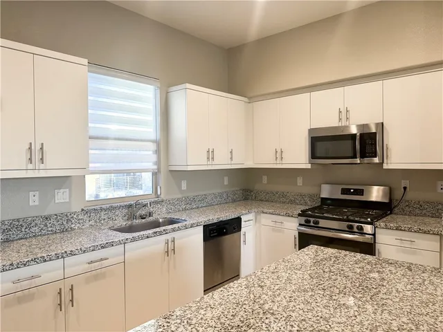 a living room with large couches and kitchen view with wooden floor