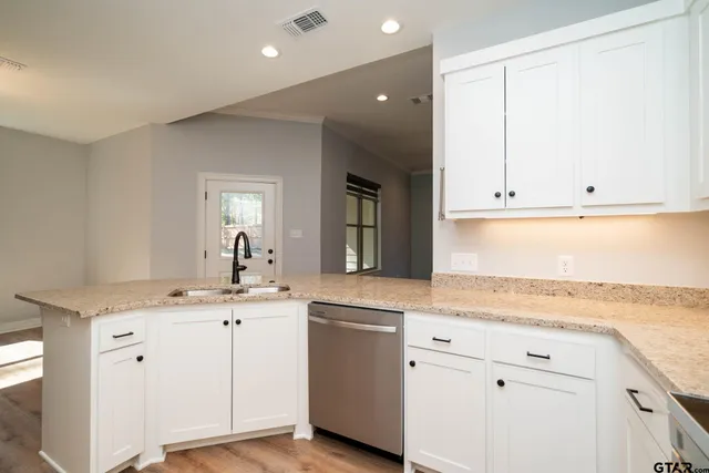 a kitchen with granite countertop white cabinets and a sink