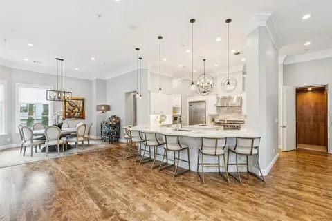 a large dining hall with stainless steel appliances granite countertop a dining table chairs and white cabinets