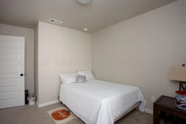 a bedroom with a bed and a lamp on the dresser