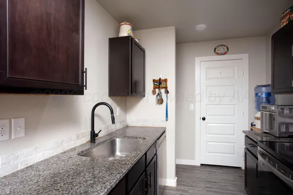 a kitchen with granite countertop a refrigerator and a stove top oven