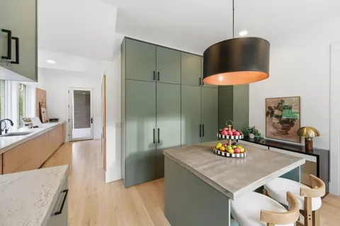 a large white kitchen with kitchen island a large counter top space a sink stainless steel appliances and cabinets