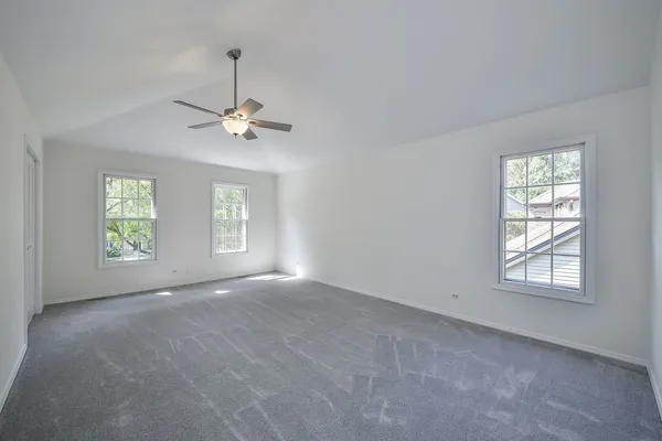 an empty room with windows and ceiling fan
