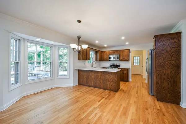 a large kitchen with stainless steel appliances granite countertop a refrigerator a sink dishwasher a stove and white countertops with wooden floor