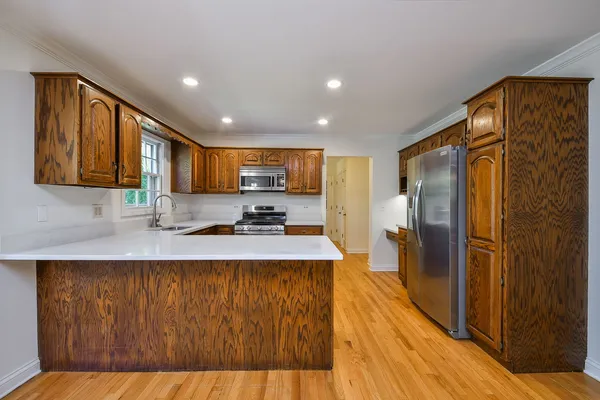 a large kitchen with stainless steel appliances granite countertop a refrigerator a stove and a wooden floors