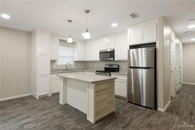 a kitchen with a refrigerator a sink and a stove top oven with wooden floor