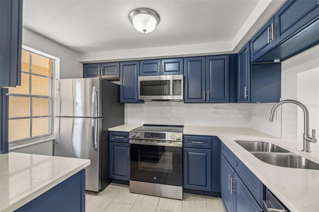 4324 Summersun Drive New Port Richey, FL 34652 - Photo 8 of 43 a kitchen with refrigerator a microwave a sink and cabinets