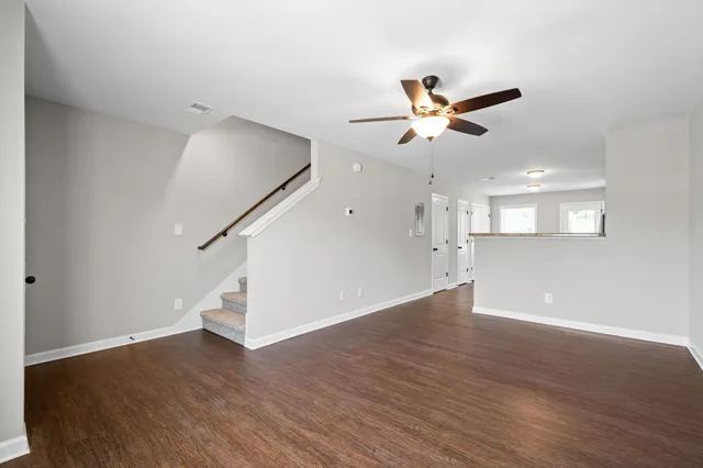 a view of an empty room with wooden floor and a ceiling fan