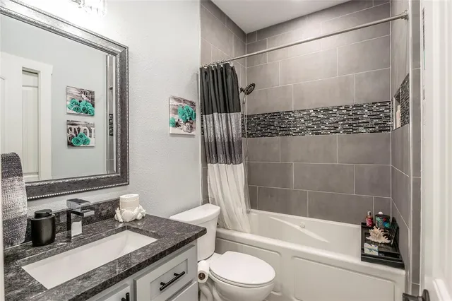 a bathroom with a granite countertop bathtub sink vanity mirror and toilet