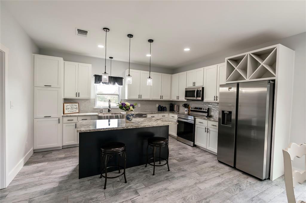 140 Lago Lane Nocona, TX 76255 - Photo 31 of 39 a kitchen with kitchen island a sink stove a refrigerator and white cabinets with wooden floor