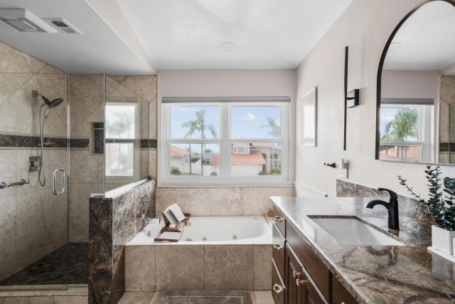 a bathroom with a granite countertop bathtub sink vanity and mirror