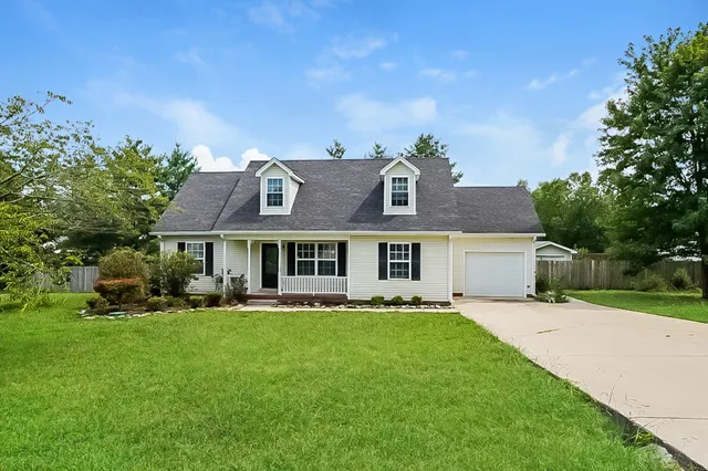 a front view of a house with a garden and trees
