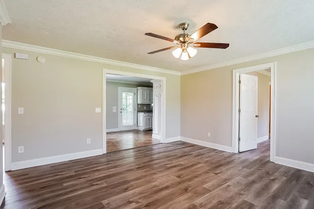 a view of an empty room with wooden floor and a ceiling fan