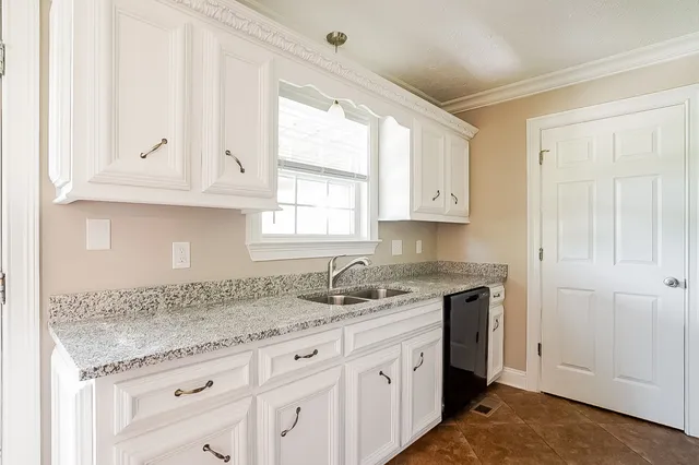 a kitchen with granite countertop white cabinets and a sink
