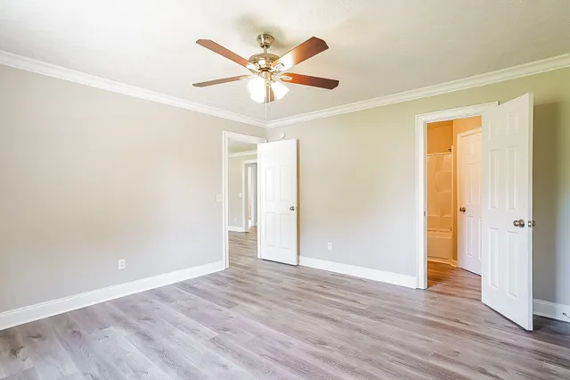an empty room with wooden floor fan and windows
