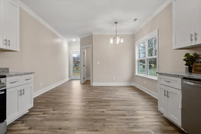 a kitchen with stainless steel appliances granite countertop a stove top oven a sink dishwasher and a refrigerator with wooden floor