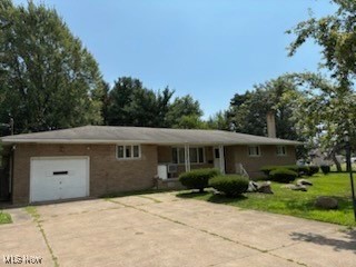 5514 Detroit Road Elyria, OH 44035 - Photo 1 of 8 Ranch-style house featuring concrete driveway, an attached garage, brick siding, a chimney, and a front yard