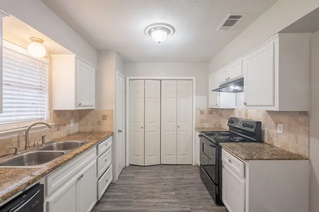 a kitchen with granite countertop white cabinets and a sink