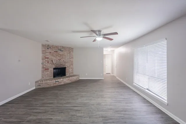 a view of an empty room with a window and a kitchen
