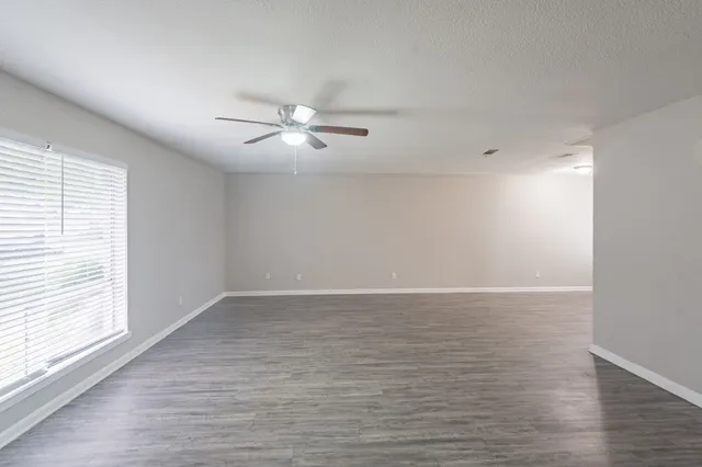a view of an empty room with wooden floor window and closet