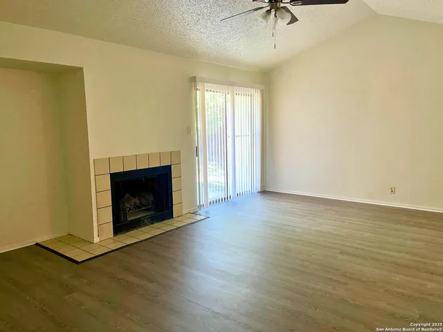 a view of an empty room with wooden floor and a fireplace