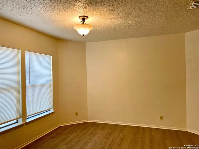 an empty room with a wooden floor and windows