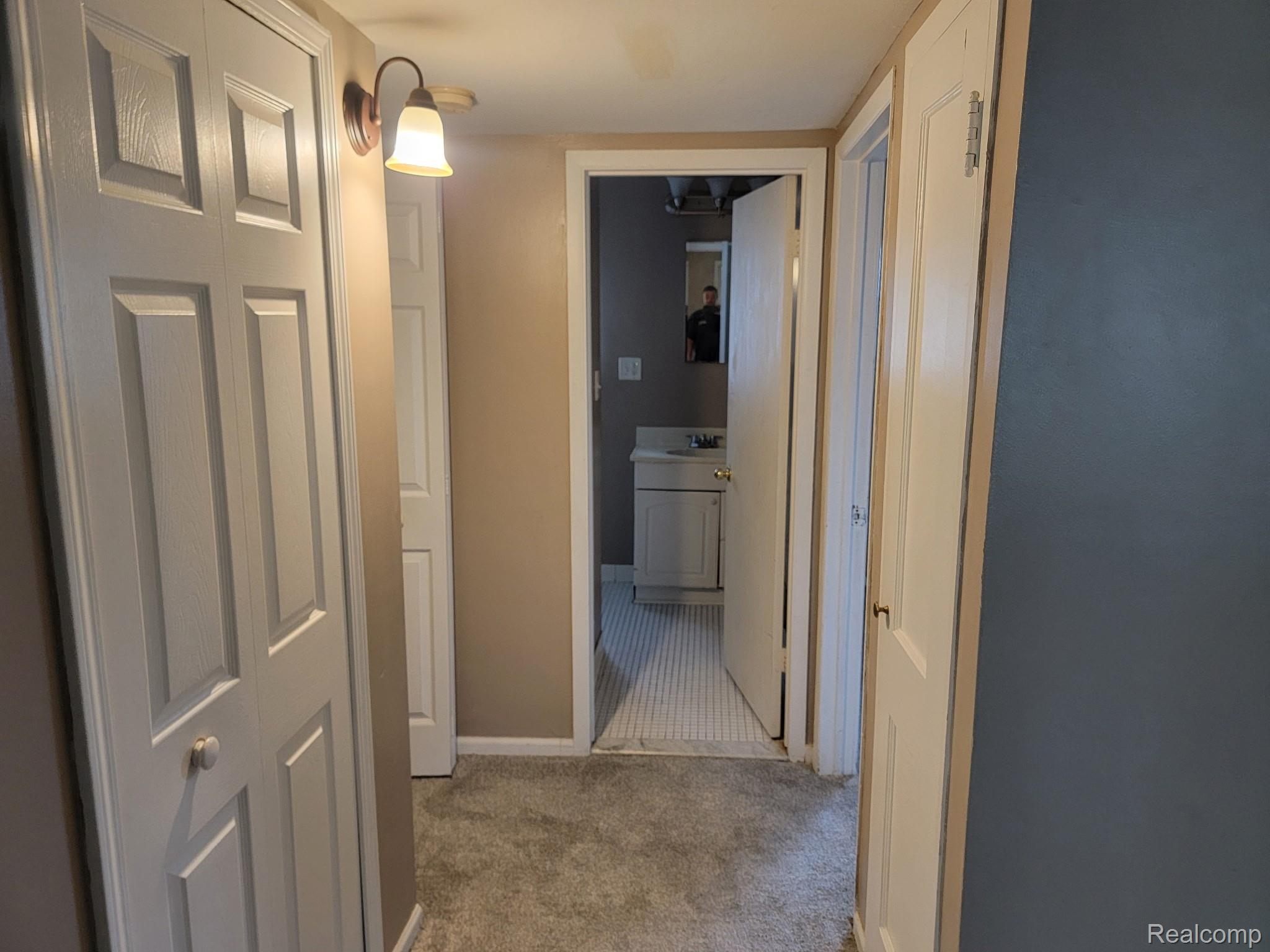 21828 Rausch Avenue Eastpointe, MI 48021 - Photo 9 of 15 Carpeted hallway with painted walls, multiple paneled doors, and an overhead wall sconce