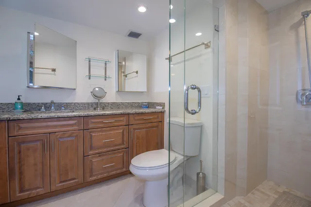 a bathroom with a granite countertop sink toilet and shower