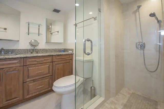 a bathroom with a granite countertop sink toilet and a mirror
