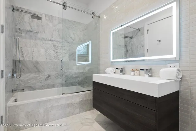 a bathroom with a bathtub sink vanity and mirror