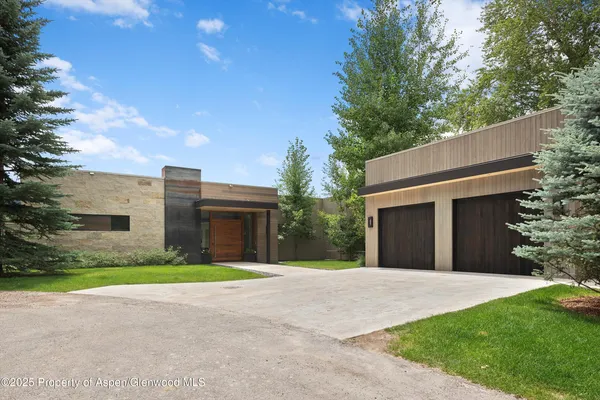 a brick house with a big yard and large trees